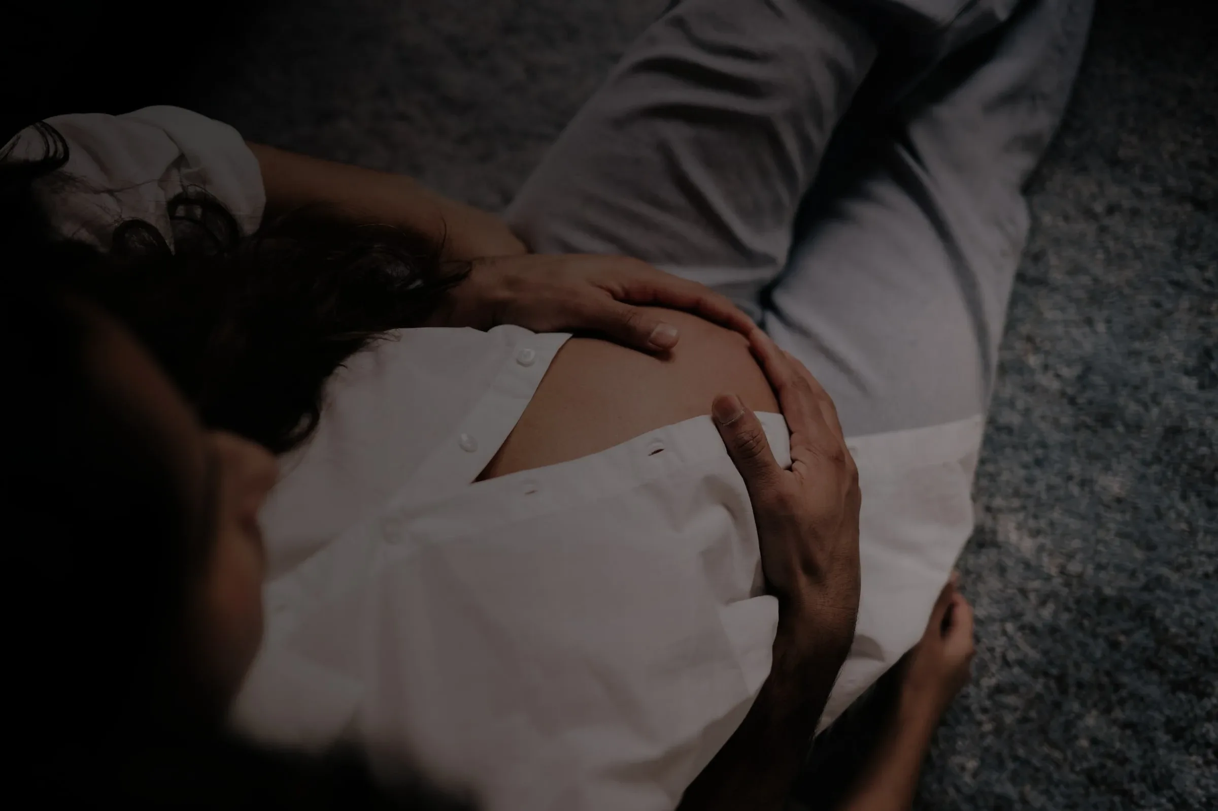 An expecting mother resting with her hands on her belly